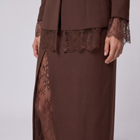 A close-up of a brown dress with a matching jacket, featuring sheer lace trim at the waist and cuffs, and a side slit showing the underlayer.