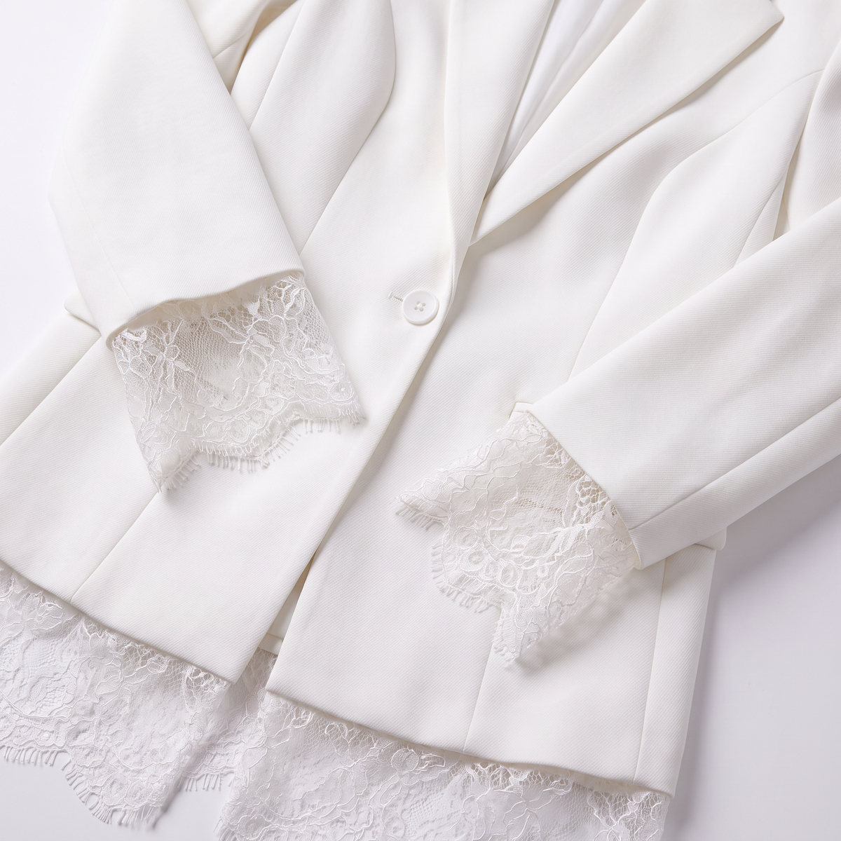 An off-white blazer with delicate white lace trim detailing the cuffs and hem, displayed on a clean white background.