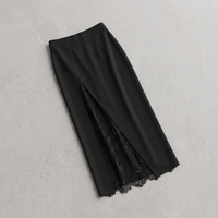A black midi skirt with a front slit revealing a black lace underlayer, laid flat on a light gray textured background.