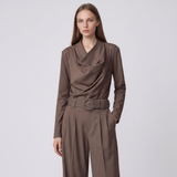 A woman modeling a brown draped long-sleeve top and matching wide-leg trousers with a matching belt, set against a plain light gray studio background.