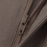 Close-up of a dark brown textured fabric zipper with a dark metallic pull tab.